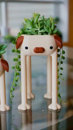 two small white dog planters sitting on top of a table