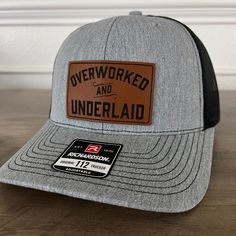 Overworked And Underlaid Funny Patch Hat. Specifications: 🧢 Richardson original 112 trucker; adjustable for the perfect fit 🎩 60/40 cotton/polyester blend for comfort 📏 One size fits most 🏷️ Expertly laser engraved leatherette patch design 📦 Ships in 2 to 3 business days from our Orlando Studio Care Instructions: 🚫 Do not wash; spot clean only Please Note: 🌈 Colors may vary from photos based on your viewing screen. This funny hat is a unique and entertaining gift for fathers, embracing th Outdoor Fitted Trucker Hat With Curved Bill, Fitted Snapback Hat With Flat Brim For Outdoor, Fitted Flat Bill Snapback Hat For Outdoor, Fitted Flat Brim Baseball Cap For Outdoor, Fitted Flat Brim Snapback Hat For Outdoor, Fitted Flat-brim Baseball Cap For Outdoor, Fitted Flat Bill Trucker Hat For Outdoor, Outdoor Fitted Trucker Hat, Fitted Trucker Hat With Curved Brim For Outdoor