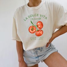 Our Comfort Colors® t-shirt, featuring "La Dolce Vita" with a vibrant tomatoes graphic, is perfect for adding a touch of Italian charm to your summer wardrobe. Ideal for a Portofino vacation or embracing a vegan lifestyle, this tomato-themed shirt blends preppy style with the essence of Italian summer. Prefer this design on a Sweatshirt? Visit this link: https://bohemianbloomdesigns.etsy.com/listing/1761622178 Prefer this design on a Baby Tee? Visit this link: https://bohemianbloomdesigns.etsy.com/listing/1775818547 👕 T-Shirt Brand Comfort Colors® 1717 | Unisex Adult Sizing | 100% Ring-Spun US Cotton ⏳🚚 Production & Shipping All items are made-to-order. They will ship within 1-5 business days from one of our printing partners, shipping usually takes between 2-5 business days after the it Organic Short Sleeve T-shirt For Spring, Organic White Short Sleeve Tops, Organic White Graphic Print Tops, Organic White Crew Neck Tops, Casual White Top With Fruit Design, Casual White Tops With Fruit Design, White Casual Top With Fruit Design, Cute Spring Tops With Fruit Design, Organic White T-shirt For Summer