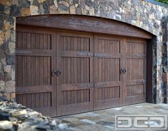 two brown garage doors in front of a stone wall