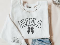 This custom nina sweatshirt is a great gift for a nina or new nina to be! This sweatshirt can be given as a gift to a friend or loved one for Mother's Day or as a baptismal gift for a godmother. This sweatshirt is made with the highest quality materials and is super comfy, soft and cozy!! Please enter the name(s) of child(ren) you would on the sleeve in the personalized section. ABOUT THIS ITEM: - Gildan Sweatshirt - Long Sleeve Crew Neck - Ribbed Neck Collar - Double-Needle Stitching - Not Viny Nina Black Swan Outfits, Nina Shirts, Dance Sister Shirt, Nana Sweatshirt Ideas, Ballet Mom Shirt, Godmother Gifts, Gildan Sweatshirts, Neck Collar, Godmother