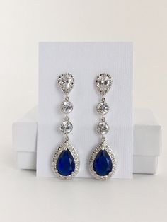 Long luxury blue sapphire cubic zirconia bridal tear dangle earrings in rhodium plated brass setting. Earrings feature a large teardrop with pear cut blue sapphire cubic zirconia center surrounded by tiny round zirconia crystals. Teardrop dangles from a bright cubic zirconia ear stud and two round cubic zirconia connectors. Total length of the earring is 6 cms. For matching necklace click: https://www.etsy.com/listing/252994446/long-blue-sapphire-cubic-zirconia-bridal?ref=shop_home_active_22 For Elegant Blue Cubic Zirconia Chandelier Earrings, Blue Cubic Zirconia Teardrop Earrings For Wedding, Blue Cubic Zirconia Dangle Chandelier Earrings, Blue Sterling Silver Chandelier Earrings For Wedding, Blue Cubic Zirconia Teardrop Earrings, Blue Teardrop Chandelier Earrings For Anniversary, Blue Cubic Zirconia Crystal Earrings For Wedding, Blue Cubic Zirconia Chandelier Earrings, Blue Pear-shaped Teardrop Earrings For Wedding