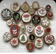 a collection of embroidered christmas ornaments on wooden slices with flowers and leaves in the center