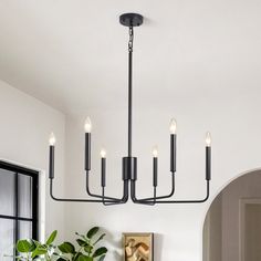 a chandelier hanging over a dining room table with potted plants on it