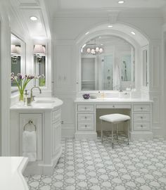 a white bathroom with two sinks and a large mirror on the wall, along with an arched doorway leading to another room