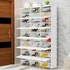 a white shoe rack filled with lots of pairs of shoes next to a brick wall