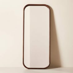 a mirror on the wall next to a white wall with a wooden frame in it