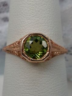 Natural Green Peridot Ring Dandelion Design#205 Custom This is a stunning Edwardian wedding reproduction gemstone filigree ring. The .85ct natural green peridot gemstone is 6mm in diameter. This lovely ring is 10K Rose Gold is marked 10K on the inner shank. Notice the beautiful craftsmanship of the rose gold filigree setting. This is an ornate and detailed ring. This is a lovely rendition of an Antique filigree wedding ring, and it is ready to wear. A ring gift box is included and all rings are Elegant Green Filigree Ring For Wedding, 14k Gold Green Rings With Intricate Design, Green 14k Gold Rings With Intricate Design, Antique May Birthstone Rings For Wedding, Antique May Birthstone Wedding Rings, Wedding Jewelry Green Stamped 14k, Green Filigree Ring With Intricate Design For Wedding, Green Oval Filigree Ring For Wedding, Green Filigree Ring For Wedding