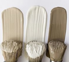 three paint brushes are lined up in the same row, one with white bristles