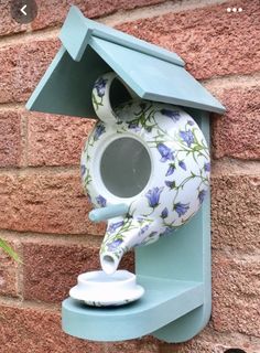 a blue birdhouse with a flowered design on it's side next to a brick wall