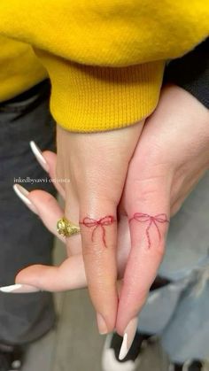 two people holding hands with tattoos on their fingers