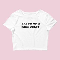 The "BRB On a Side Quest" Women's Crop Baby Tee is a stylish and unique t-shirt designed for music festival-goers and fans of the Y2K rave culture. This crop top combines a playful design with a trippy aesthetic, making it a standout choice for those seeking an eye-catching and unconventional look. With its cropped design, this tee is perfect for pairing with high-waisted bottoms like skirts, shorts, or jeans, allowing you to create a trendy and fashionable outfit. The "BRB On a Side Quest" grap Fitted Rave T-shirt For Streetwear, Punk Short Sleeve Crop Top With Letter Print, Punk Style Short Sleeve Tops For Music Festival, Summer Graphic Tee With Band Logo, Trendy Short Sleeve Crop Top For Music Festival, Crew Neck Letter Print Tops For Music Festival, Crew Neck Tops With Letter Print For Music Festival, Punk Slogan T-shirt For Summer, Music Festival Crew Neck Tops With Letter Print