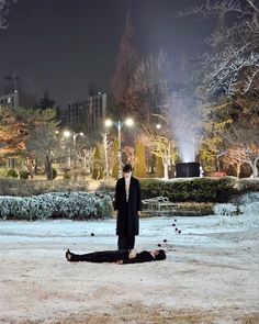 a man in a suit and tie standing next to a person laying on the ground