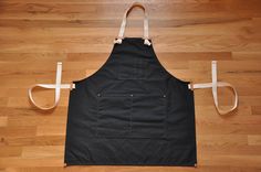 a black apron with white straps is on the floor