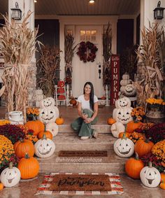 a woman is sitting on the steps decorated with pumpkins