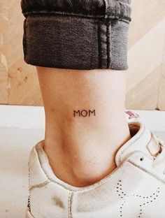 a woman's foot with the word mom tattooed on her left side ribcage