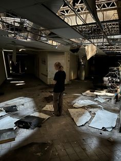 a woman standing in an empty room with lots of paper on the floor