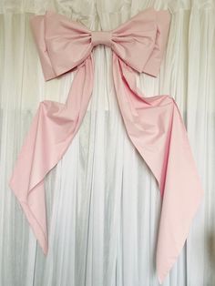 a pink bow hanging on the side of a white curtain