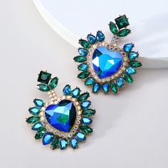 These Big Heart Halo Luxury Glass Formal Dangle Drop Statement Earrings boast a striking combination of vibrant crystal color and rhinestone inlay, creating an eye-catching heart design. The perfect addition to any formal outfit for an opulent and sophisticated look. Available in 5 different colors. Details Item Type: Fashion Earrings Metal Type: Zinc Alloy Material: Acrylic,Rhinestone Size: 6.1*4.9cm Back Finding: Push Back Statement Wedding Jewelry, Big Dangle Earrings, Heart Halo, Romantic Luxury, Earrings Model, Popular Earrings, Ear Accessories, Wedding Party Jewelry, Statement Drop Earrings