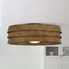 a wooden light fixture hanging from the ceiling in a room with white walls and cabinets