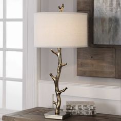 a table lamp with a bird on it and a white shade in front of a window