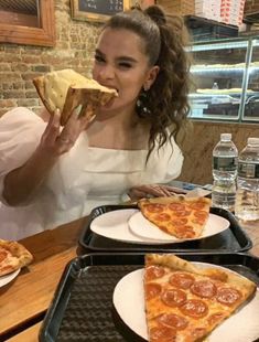 a woman is eating pizza at a restaurant