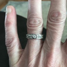 a person's hand with a wedding ring on top of their finger and the other half of their thumb