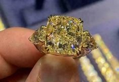 a yellow diamond ring is being held by someone