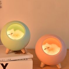 two colorful lights sitting on top of a white book next to a vase with flowers