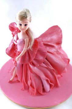 a barbie doll figurine sitting on top of a pink plate