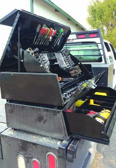 an open tool box sitting in the back of a pickup truck with tools inside it