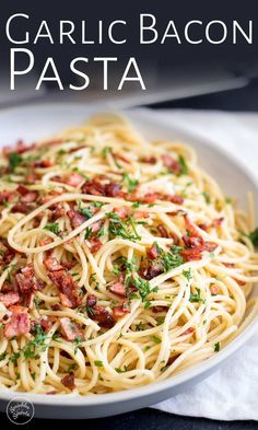 a white plate topped with pasta covered in bacon