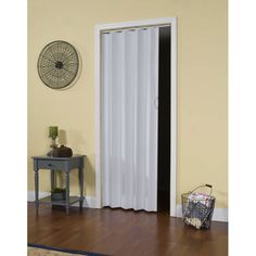 an open door with white curtains in a living room next to a table and chair