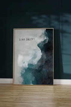 a black and white poster with the words stay salty on it in front of a wooden floor