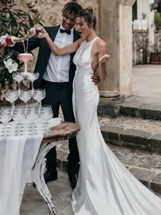 a man and woman standing next to each other in front of a table filled with wine glasses