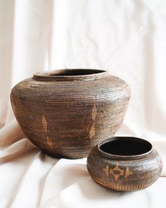 two brown vases sitting on top of a white cloth covered floor next to each other