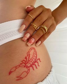 a woman's stomach with a scorpion tattoo on her belly and two gold rings