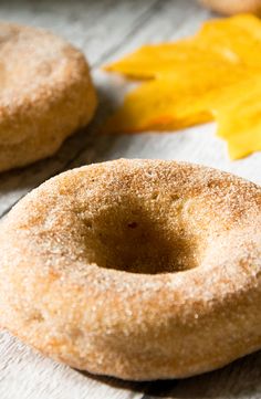 two doughnuts sitting on top of a table next to an orange maple leaf