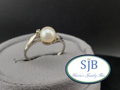 Previously Loved🥰Not New ⚪️Vintage Pearl &💎 Ring⚪️ Another Absolutely AMAZING Find Featuring a Timeless Pearl Bypass Ring Design. Built in all Shining 14k White Gold 🪩 Set with a Shimmering Genuine Creamy White Saltwater Pearl ⚪️ Gemstone with a Glowing Pink luster measuring approximately 6.4mm, with a prong-set Sparkling Genuine/Natural Earth 🌎 Diamond 💎💎 on each side totaling 💎💎 .02cts together. This AMAZING Pearl and Diamond Ring is PERFECT for your upcoming Wedding or Anniversary a T White Gold Pearl Ring Stamped 14k For Gift, Oval Pearl Solitaire Ring For Anniversary, 14k White Gold Pearl Ring Gift, Oval Pearl Ring With Center Stone For Anniversary, White Hallmarked Birthstone Wedding Ring, Heirloom White Gold Pearl Ring Stamped 14k, White Hallmarked Birthstone Ring For Anniversary, White Rings Stamped 14k For Anniversary, White Heirloom Birthstone Ring For Formal Occasions