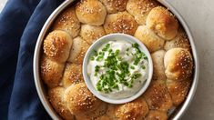 a bowl filled with bread rolls covered in sour cream and topped with green chives