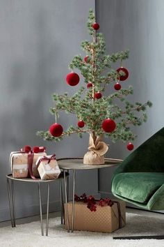 a small christmas tree sitting on top of a table next to a green chair and presents