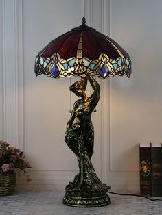 a lamp with a lady holding a bird on it's arm next to a book