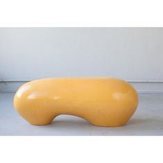 a large yellow object sitting on top of a cement floor next to a white wall