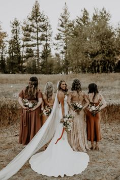 a group of women standing next to each other wearing dresses and holding bouquets in their hands