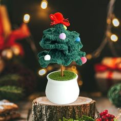 a small crocheted christmas tree sitting on top of a wooden stump next to other decorations