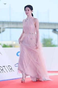 a woman in a pink dress walking down a red carpet with her hand on her hip