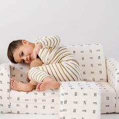 a young boy laying on top of a white couch