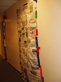 a bulletin board is covered with newspaper and red, green, blue, and yellow streamers