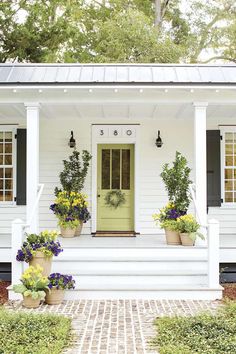 a white house with potted plants on the front porch