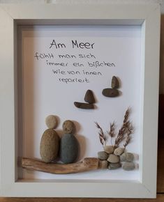 a white frame with some rocks and a wooden stick in it that says, am meer